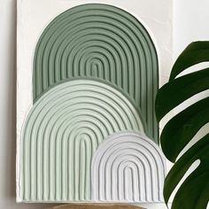 a green plant sitting next to a painting on top of a wooden table in front of a white wall