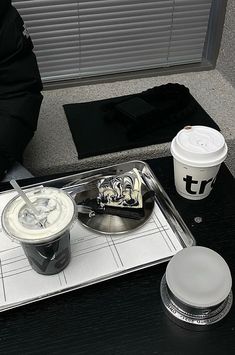 there is a tray with two cups and a spoon on the table next to it