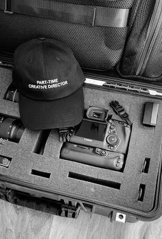 a black and white photo of an open suitcase with items in it, including a hat