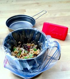 a pot and pan sitting on top of a wooden table next to a plastic bag