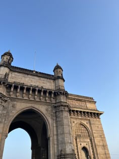 an old stone arch with two clocks on it's sides and a blue sky in the background