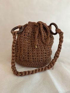 a crocheted brown purse with handles on a white background, the bag is made out of yarn