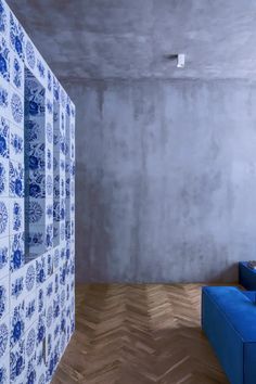 an empty room with blue and white tiles on the wall, couches and mirror