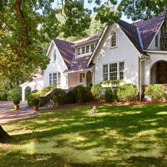 a large white house sitting in the middle of a lush green field with lots of trees