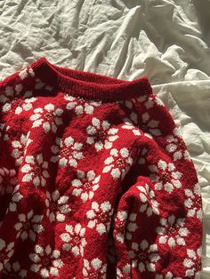 a red and white sweater laying on top of a bed