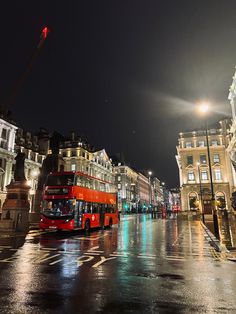 a red double decker bus driving down a street at night