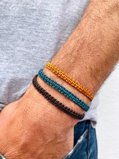 a man wearing three different colored bracelets on his arm with one yellow and the other blue