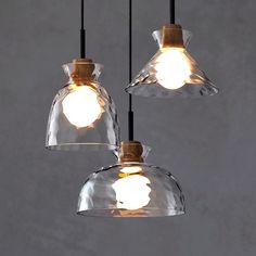 three clear glass pendant lights hanging from a ceiling