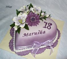 a purple heart shaped cake with flowers on it