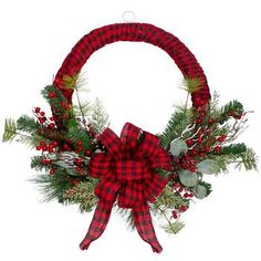 a christmas wreath with red and black plaid bow hanging from it's front door