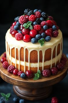 a cake with berries, raspberries and blueberries on top sitting on a wooden stand