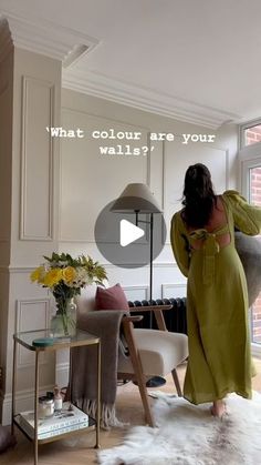 a woman in a green dress is looking into a living room with white walls and flooring