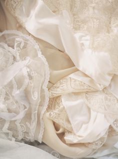 white fabric and laces are piled on top of each other in this image, the material is unbuttoned