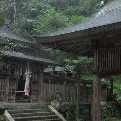 an old wooden building in the woods with stairs leading up to it's roof