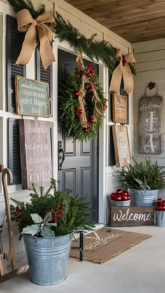 two buckets filled with christmas wreaths on the front porch next to a welcome sign