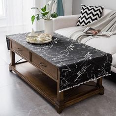 a living room with a couch, coffee table and potted plant on top of it