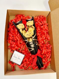 a box with some teddy bears in it and red petals on the floor next to it