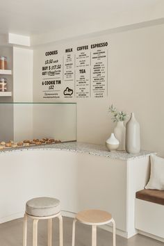 there is a coffee shop with two stools in front of the counter and menu on the wall