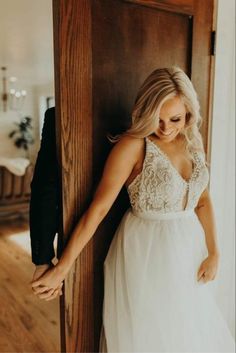 a woman in a white dress leaning against a wall with her hand on the door