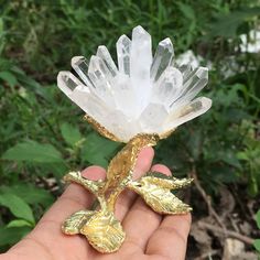 a hand holding a crystal flower with leaves on it