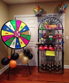 a wheel of fortune display in a room with balloons and confetti on the floor