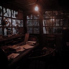 a dark room with lots of windows and papers on the desk in front of it