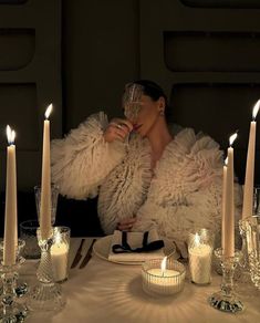 a woman sitting at a table with candles and wine glasses