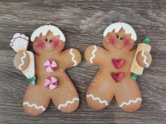 two gingerbread men holding candy canes on top of a wooden table next to each other