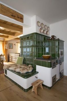 an old fashioned kitchen with green tiles and wood flooring in the living room area