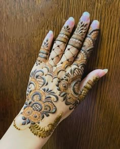 a woman's hand is decorated with hennap and gold designs on it