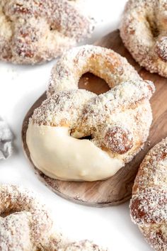 powdered sugar covered donuts sitting on top of a wooden board next to other doughnuts