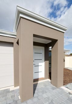 a white door is open in front of a tan building with two garage doors on each side