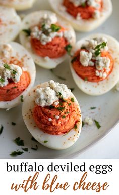 deviled eggs with red sauce and feta cheese on a white plate, ready to be eaten