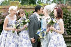 a group of people standing next to each other in front of flowers and bushes with one man kissing the woman's forehead