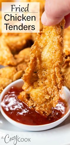 fried chicken tenders being dipped in ketchup on a plate with dipping sauce