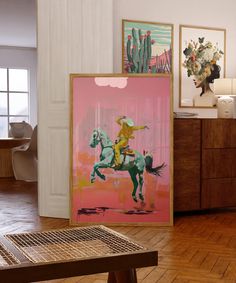 two paintings on the wall in a room with wooden flooring and wood furniture, along with a coffee table