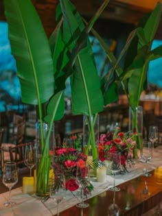 there are many vases with flowers and greenery on the table at this wedding reception