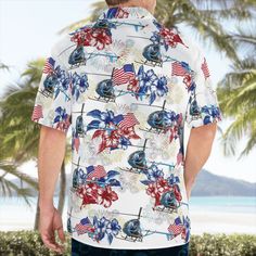 a man standing on the beach wearing a hawaiian shirt with an american flag and helicopter design