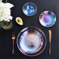 the table is set with plates, silverware and an avocado