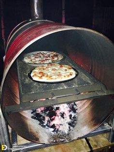 two pizzas are cooking in an outdoor oven