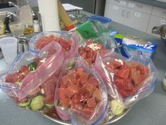 plastic bags filled with meat and vegetables on a kitchen counter top next to other food items