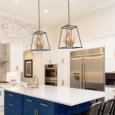 a kitchen with white cabinets, blue island and gold accents on the wall behind it