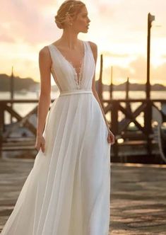 a woman in a white dress standing on a dock