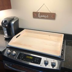 a stove top with a wooden cutting board on it