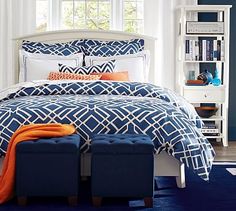 a blue and white bed with orange pillows