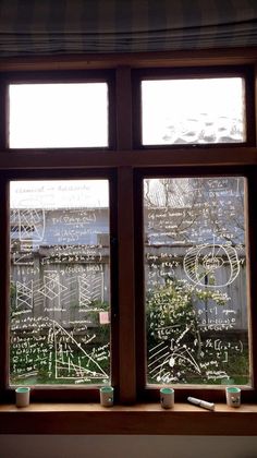 a window with writing drawn on it and cups in front of the windows sill