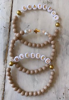 "Your choice of 1, 2 3 or 4 . Beaded bracelets in a pretty neutral shade... \"latte\" or rose beige. Accented with crystal and brushed gold and pearl. Does come in silver ( with white and black letters) available on request. Sizes Small 6.5 ( fits more snug) Medium 7 Large 7.5 Extra large 8 If you choose the set of two please let me know what word you would like ( custom words welcome) For example in the personalization section write: blessed bracelet plus cross bracelet Or... blessed and Gratef Stackable Bracelets Beaded, Things To Write On Bracelets, Christian Bracelets Diy, Christian Beaded Bracelets, Homemade Beaded Bracelets, Grateful Bracelet, Blessed Bracelet, Beaded Name Bracelet, Bracelets Pearl