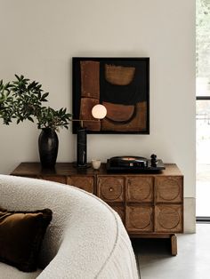 a white couch sitting next to a table with a potted plant on top of it