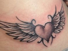 a heart with wings tattoo on the side of a woman's stomach and chest