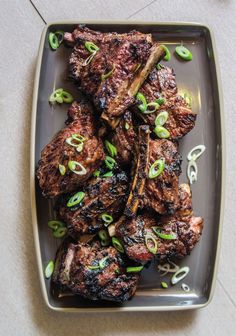 some meat is on a plate with scallions and green onions around it,